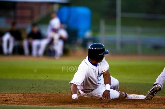 Joueur de baseball glissant sur une base A — Photo de stock