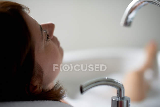 Gros plan d'une femme mûre les yeux fermés dans la baignoire — Photo de stock