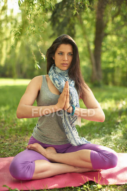 Спокійна і мирна жінка практикує усвідомлення, роздумуючи в природі під час заходу сонця — стокове фото