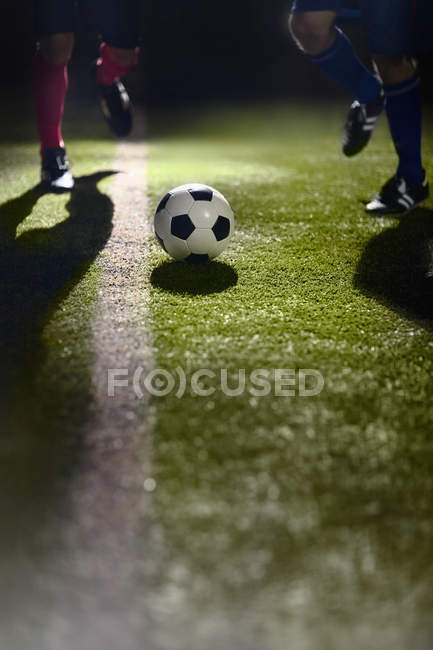 Jogadores de futebol correndo em direção a uma bola de futebol — Fotografia de Stock