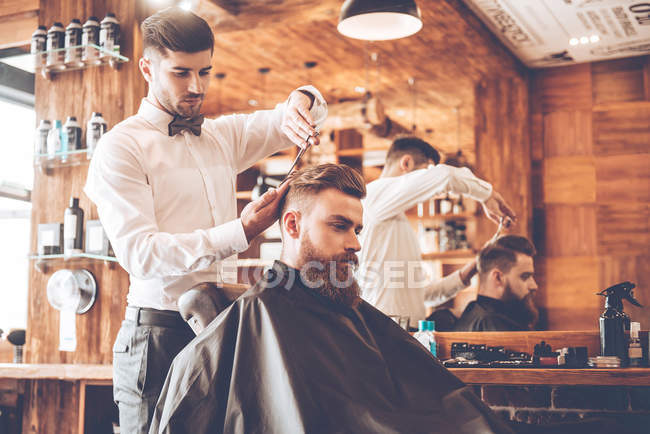 Giovane uomo barbuto con parrucchiere — Foto stock