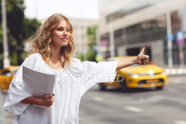 Business woman holding documents and taxi stops — Stock Photo