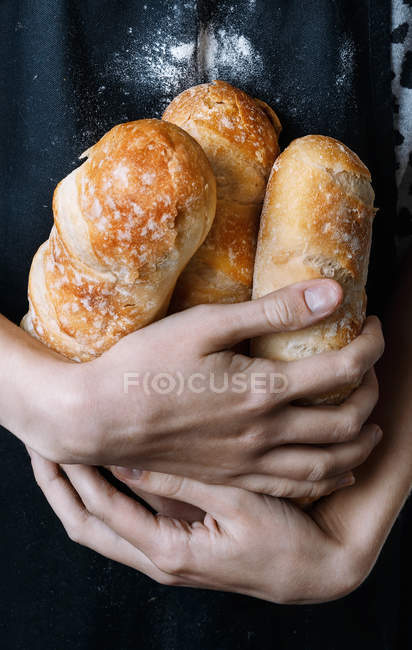 Baker hands holding fresh baked bread — Stock Photo