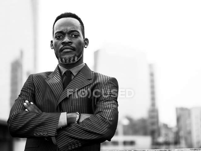 Retrato de hombre de negocios africano en la ciudad con brazos cruzados - foto de stock