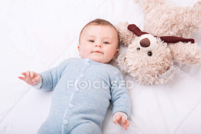 Малыш лежит в постели со своей игрушкой. . — стоковое фото