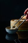 Recortado disparo de persona sosteniendo palillos y comiendo deliciosa comida asiática tradicional - foto de stock
