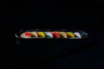 Colorful sweet macaroons cakes in a row on black background — Stock Photo