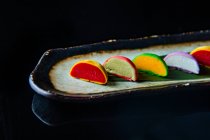 Bolos de macaroons doces coloridos em uma fileira no fundo preto — Fotografia de Stock