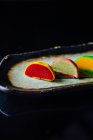 Coloridos pasteles de macarrones dulces en una fila sobre fondo negro - foto de stock