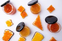 Frascos de caviar rojo y tostadas con mantequilla y diferentes tipos de caviar rojo sobre el fondo blanco - foto de stock
