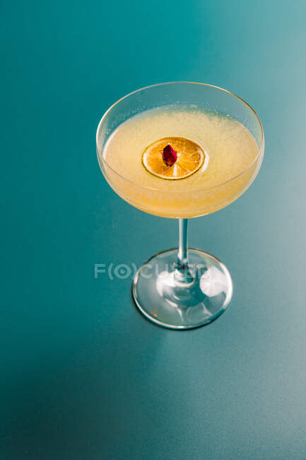 Close-up view of glass with cocktail with ice and lemon on blue background — Stock Photo