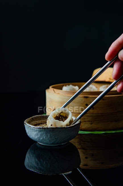 Abgeschnittene Aufnahme einer Person, die Essstäbchen hält und köstliche traditionelle asiatische Mahlzeit isst — Stockfoto