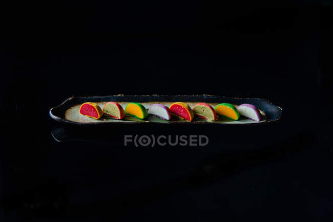 Bunte süße Makronen Kuchen in einer Reihe auf schwarzem Hintergrund — Stockfoto