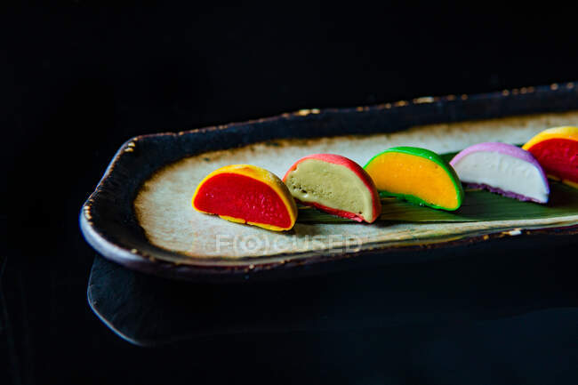 Bolos de macaroons doces coloridos em uma fileira no fundo preto — Fotografia de Stock