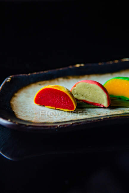 Coloridos pasteles de macarrones dulces en una fila sobre fondo negro - foto de stock