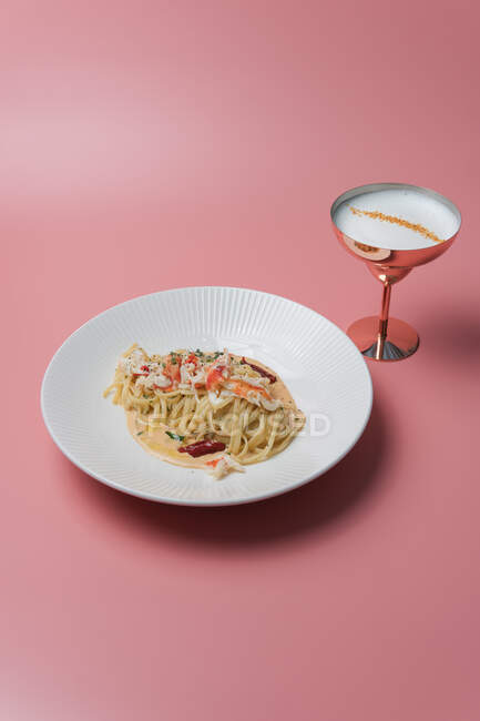 Спагетті з морепродуктами та сирним соусом на тарілці на рожевому фоні — стокове фото