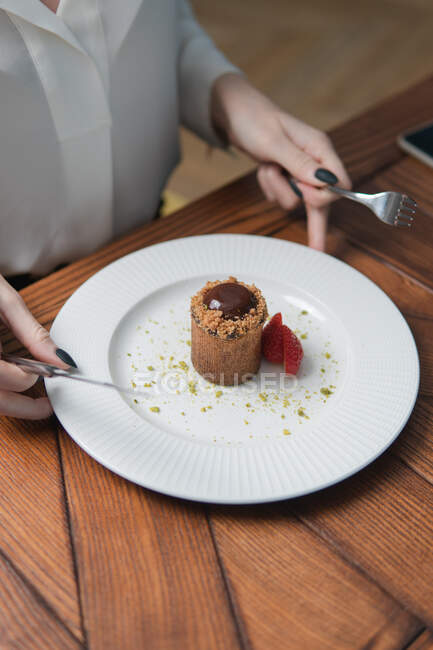 Schnappschuss einer Person, die leckeres süßes Dessert mit Schokoladencreme und Erdbeeren isst — Stockfoto
