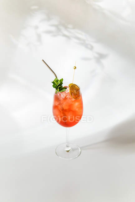 Cóctel rojo en vaso con hielo y hojas de menta sobre fondo blanco - foto de stock
