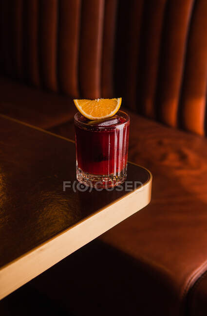 Cocktail com fatia de laranja em vidro na mesa no pub com fundo escuro. Foto de alta qualidade. — Fotografia de Stock
