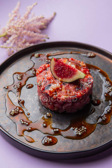 Vista de primer plano de un plato de tártaro con salsa roja e higos - foto de stock