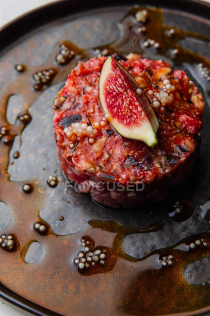 Vue rapprochée d'une assiette de tartare avec sauce rouge et figues — Photo de stock