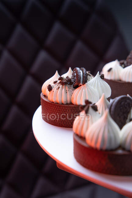 Deliciosos cupcakes con glaseado blanco y galletas en un plato blanco - foto de stock