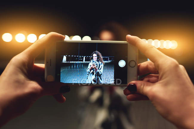Крупним планом зображення жінки робить фотографію молодої дівчини-гіпстера з цифровою камерою смартфона під час виходу на вулицю ввечері . — стокове фото