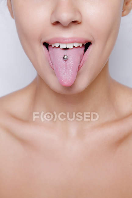Bella donna sporgente la lingua e mostrando giovane piercing — Foto stock
