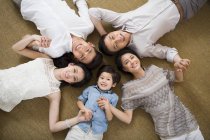 Китайская семья три поколения держалась за руки, лежа на полу — стоковое фото