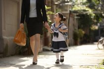 Mother walking with schoolgirl on street — Stock Photo