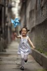 Criança chinesa correndo com papel pinwheel — Fotografia de Stock