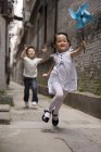 Chinese children running with paper pinwheel — Stock Photo