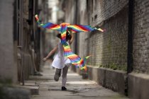 Menina correndo com pipa colorida no beco — Fotografia de Stock