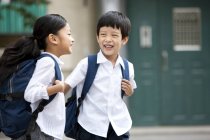 Chinese children with backpacks laughing on street — Stock Photo