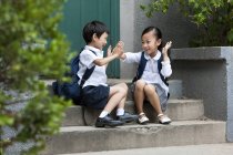 Niños de escuela chinos jugando en los escalones - foto de stock