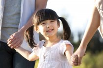 Menina chinesa com tranças de mãos dadas com a família no prado de verão — Fotografia de Stock