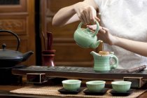 Woman in traditional cheongsam pouring tea into teapot — Stock Photo