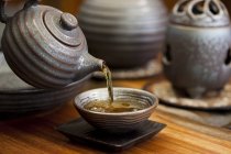 Tea pouring from chinese teapot into cup — Stock Photo