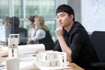 Chinese architect thinking with colleagues in background — Stock Photo