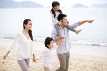 Família chinesa passeando na praia e apontando para a vista — Fotografia de Stock