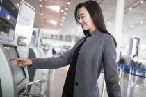 Asiatin benutzt Fahrkartenautomaten am Flughafen — Stockfoto