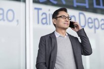 Азиатский мужчина разговаривает по телефону в аэропорту — стоковое фото