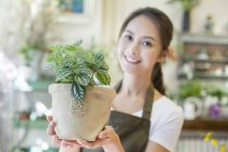 Feminino florista chinês segurando vaso planta na loja — Fotografia de Stock