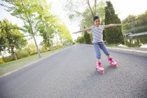Chinese girl roller skating on park road — Stock Photo