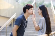 Mujer china poniendo smartphone para beso novio - foto de stock