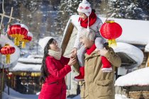 Chinesischer Vater trägt Tochter mit Laterne auf Schultern, während Mutter zusieht — Stockfoto