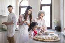 Chinese family making dumplings in kitchen — Stock Photo