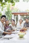 Chinese multi-generation family sitting at dining table in courtyard — Stock Photo