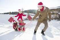 Chinese parents carrying sled with children and Christmas presents — Stock Photo