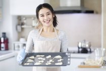 Asiatin hält Tablett mit Keksen in Küche — Stockfoto